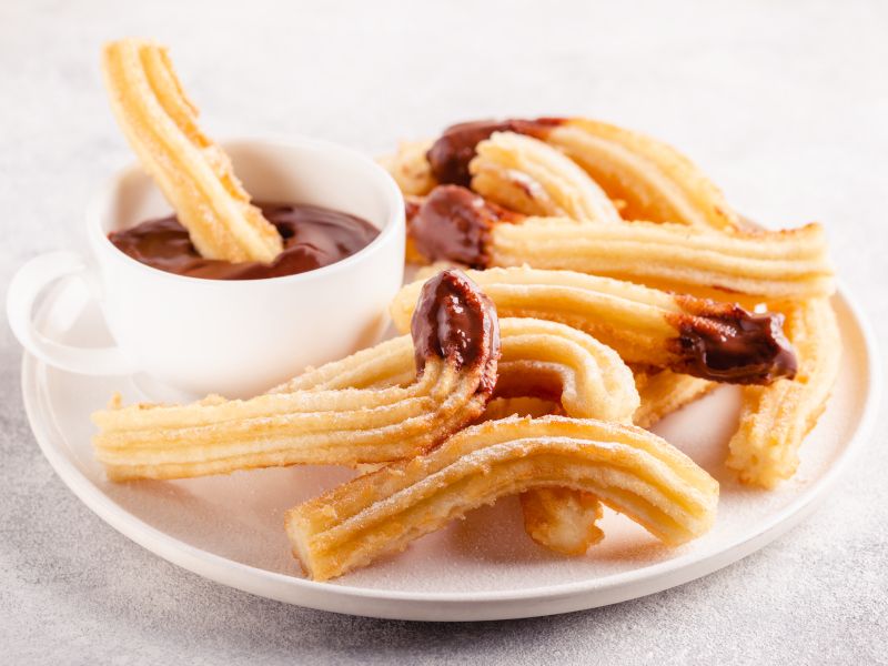 Plato de churros con una taza de chocolate.